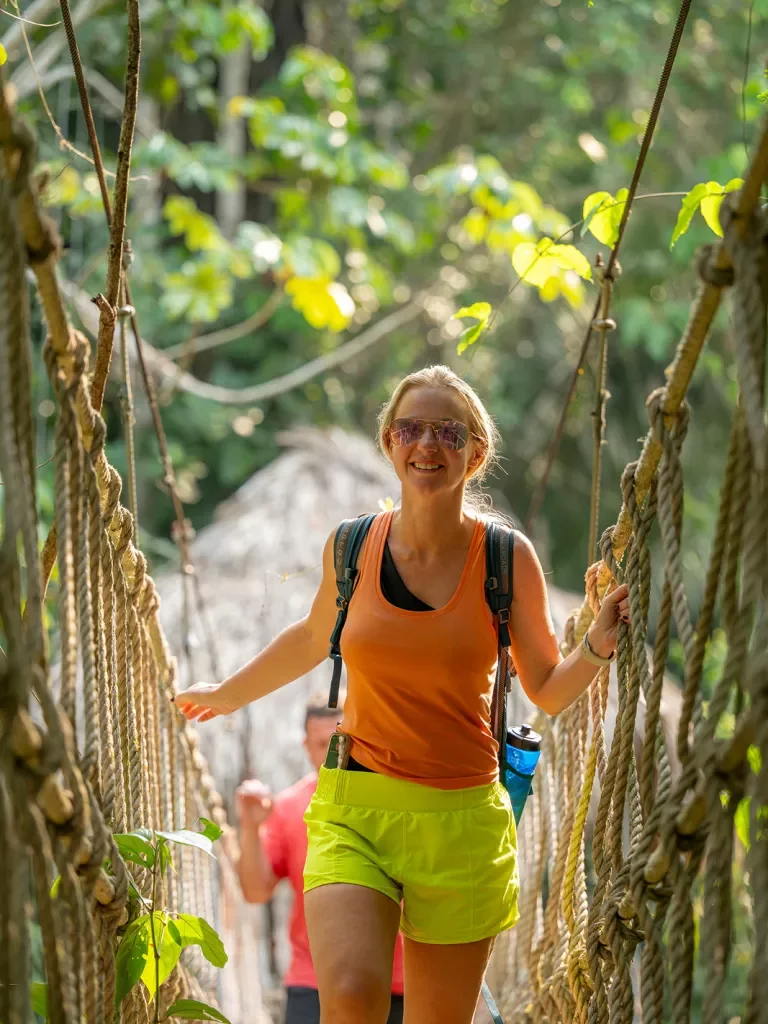 Female walking along a rope bridge in the forest
