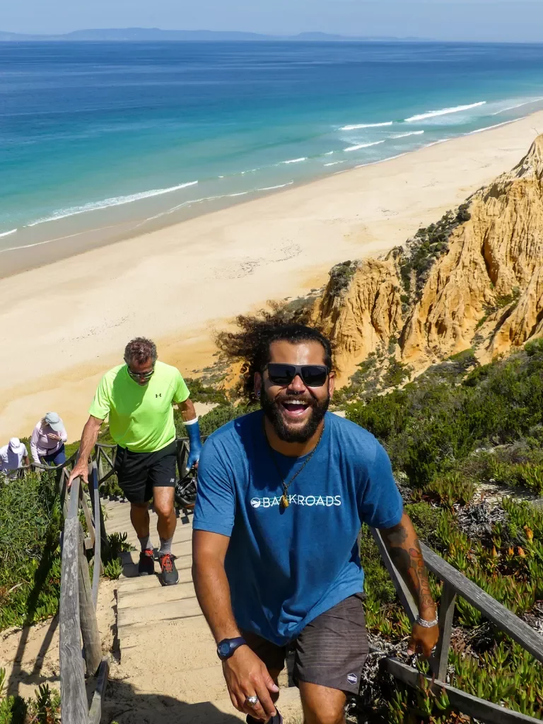 Man with blue shirt climbing up a flight of stairs on the beach