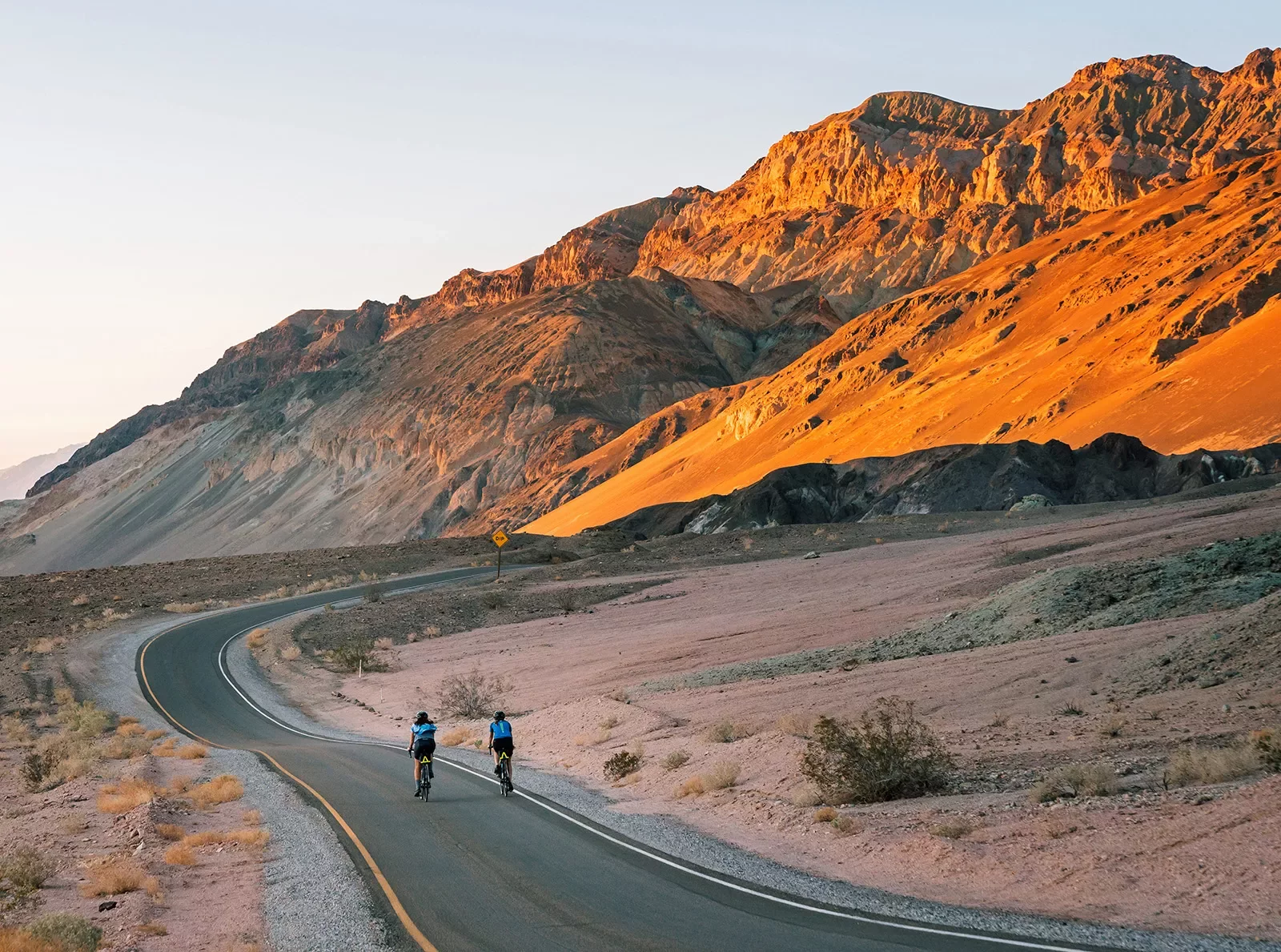 Guests riding down desert road during sunset.