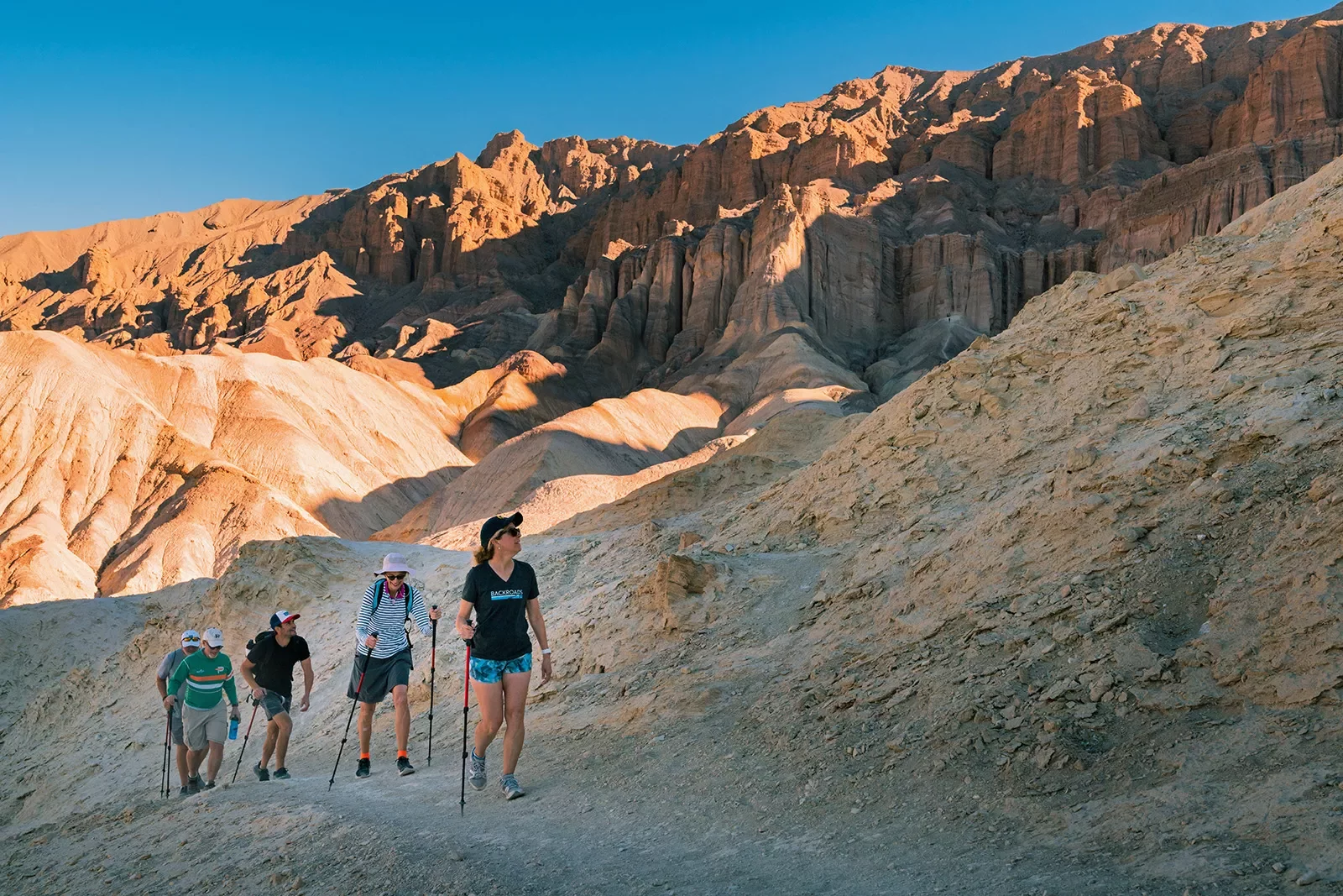 Guests hiking among craggy,, amber desert hills.
