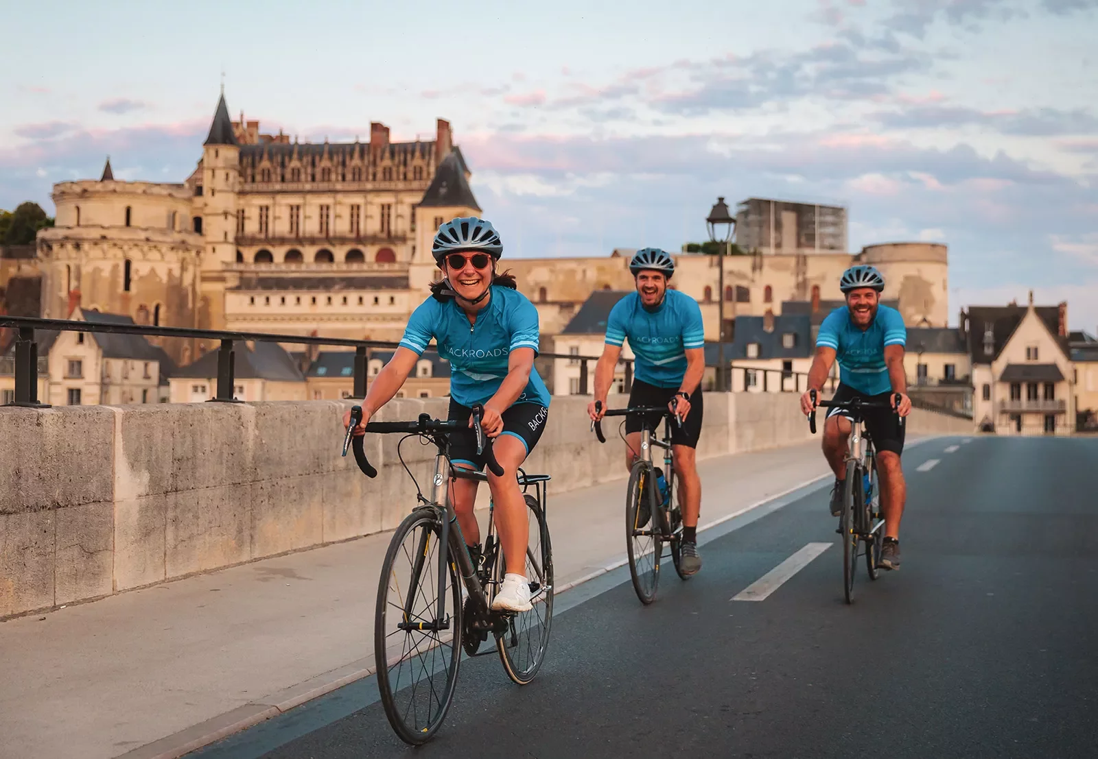 Three guests cycling in French town, Château Royal d'Amboise in background.