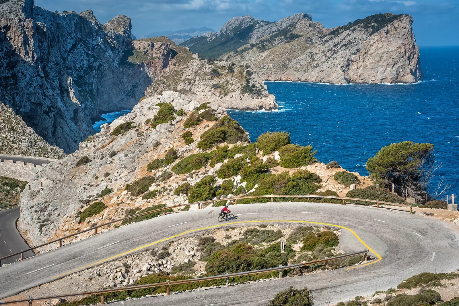 Biker riding around a bend on the coast of Mallorca.
