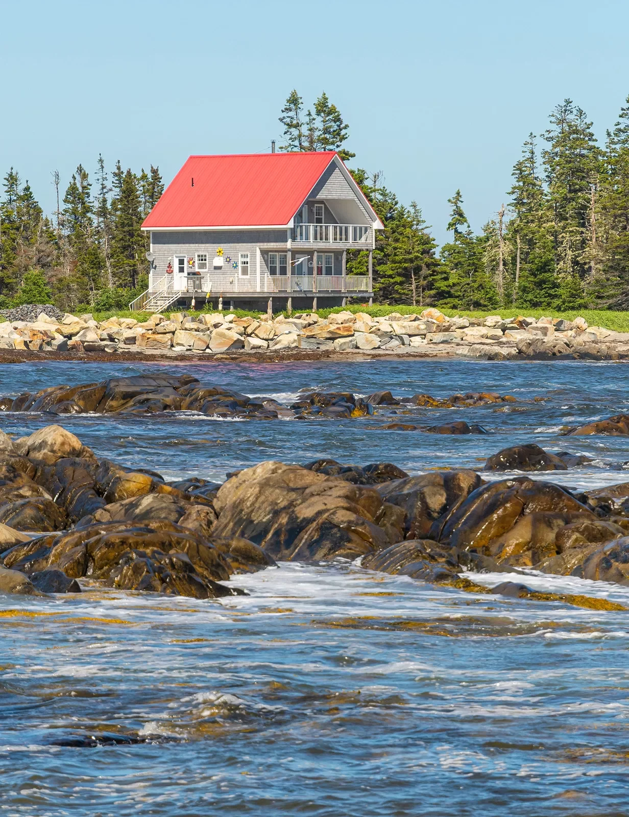 Rocky ocean shore in foreground, two-story fishing house in background.