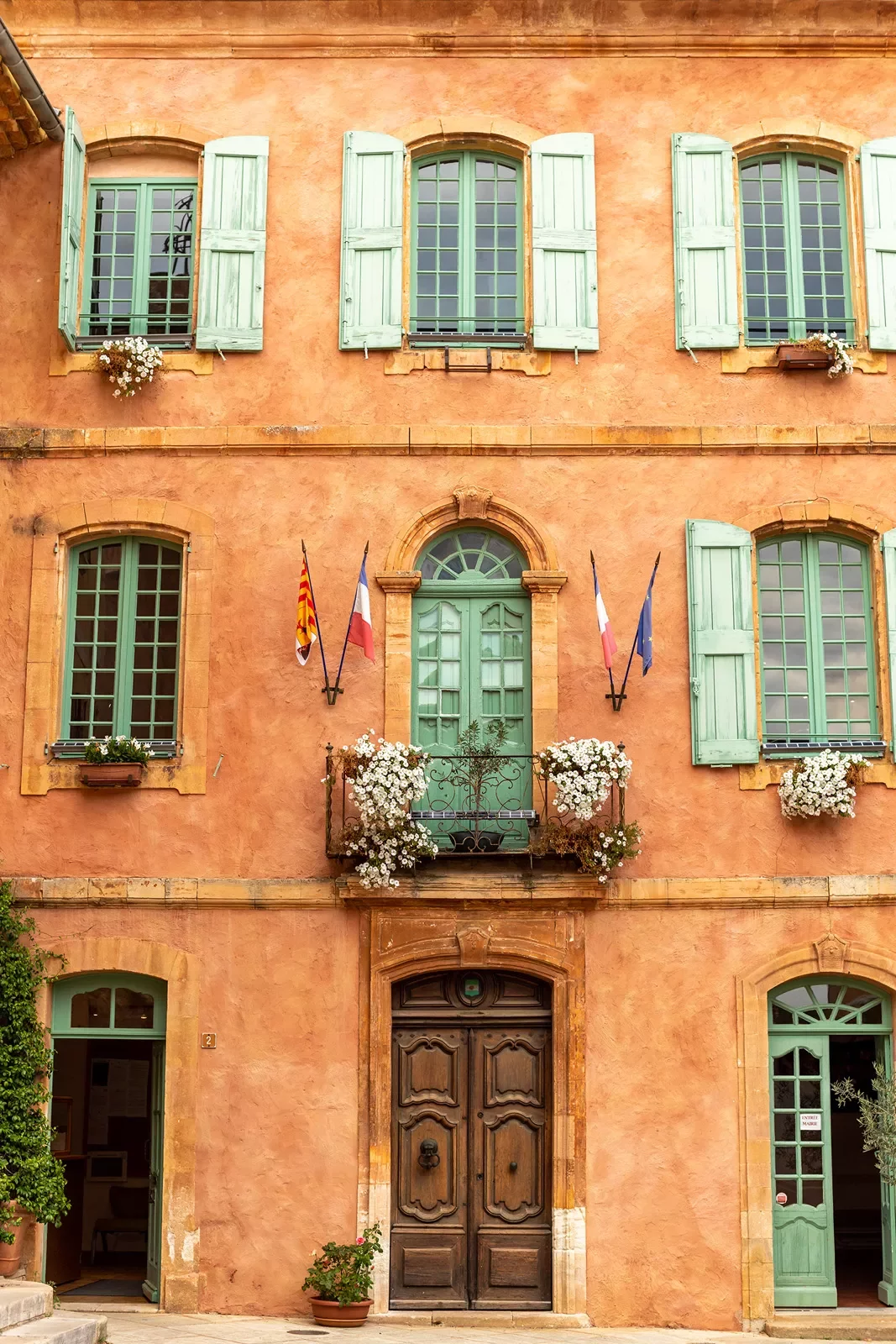 Shot of orange building, flags, balcony, windows, wood door.