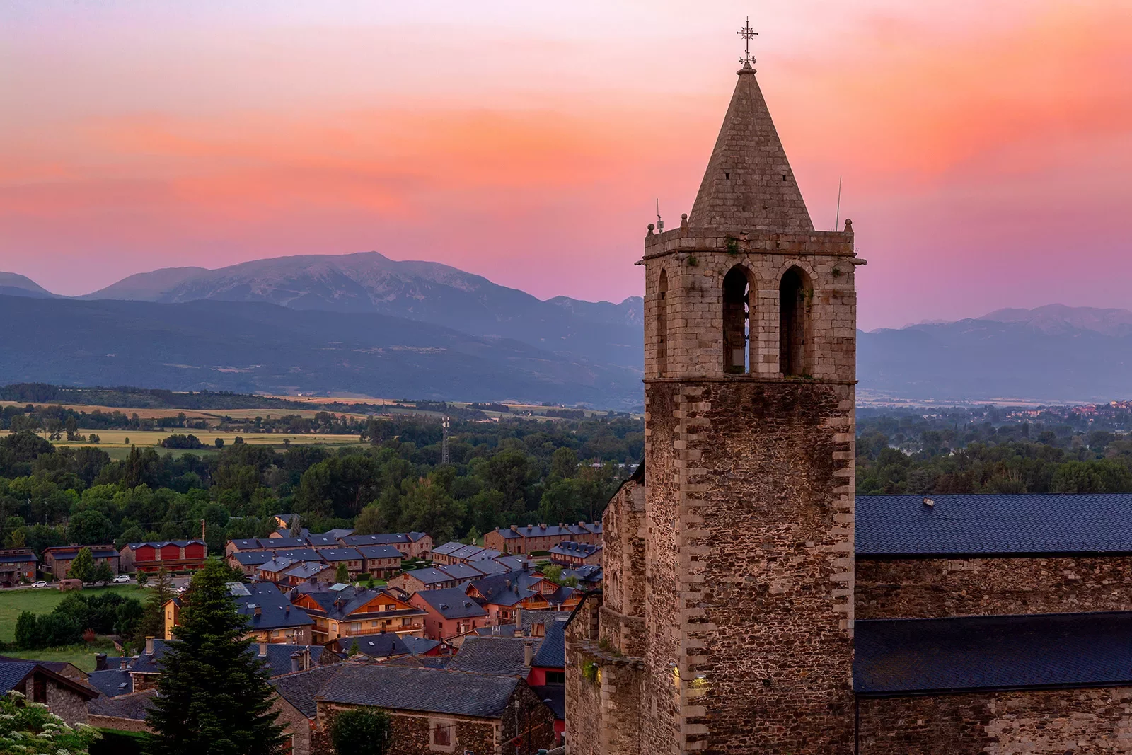 Shot of Spanish village during sunset, large church clock-tower at center.