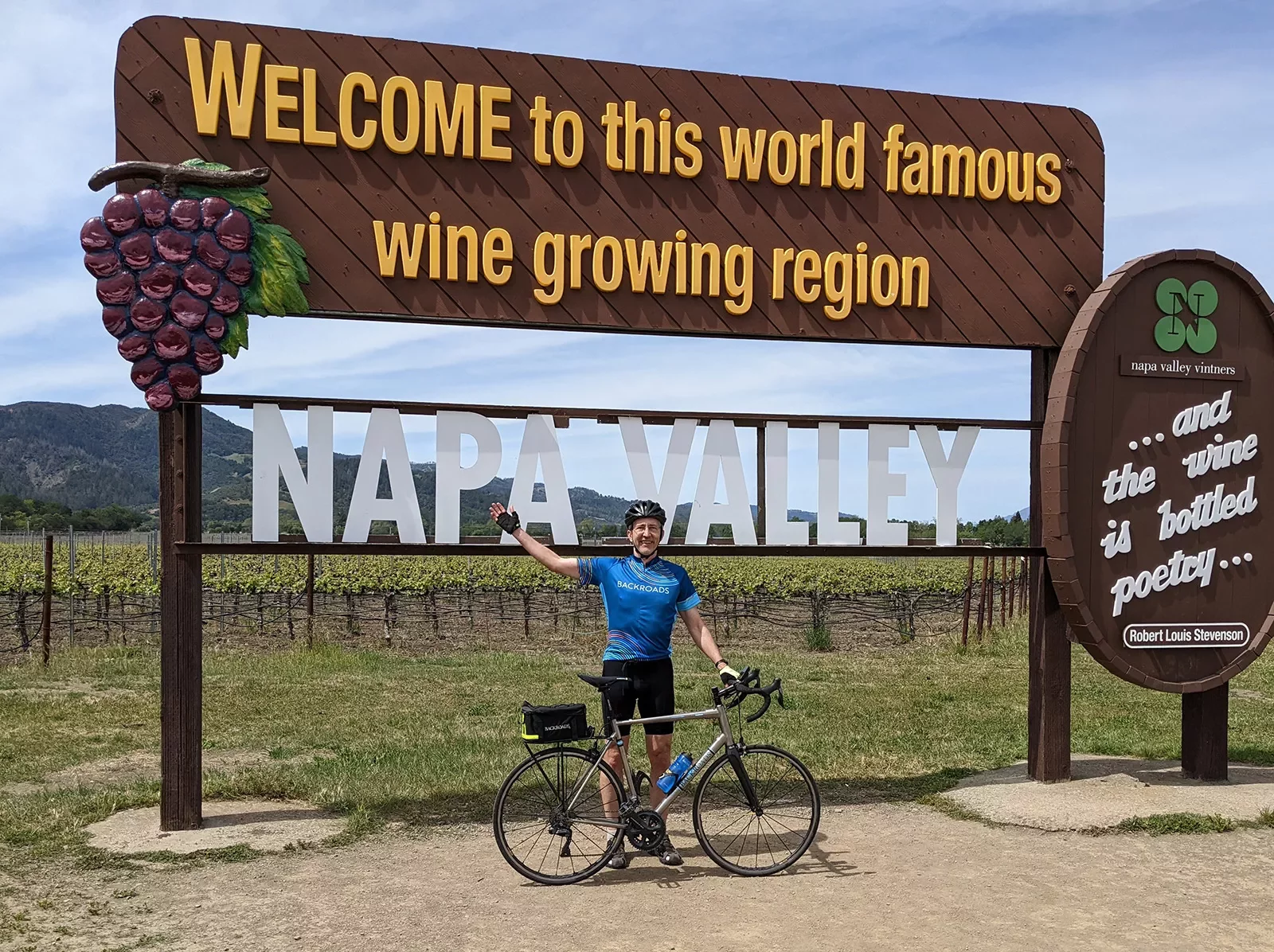 Guest with bike in front of &quot;WELCOME TO NAPA VALLEY&quot; sign.
