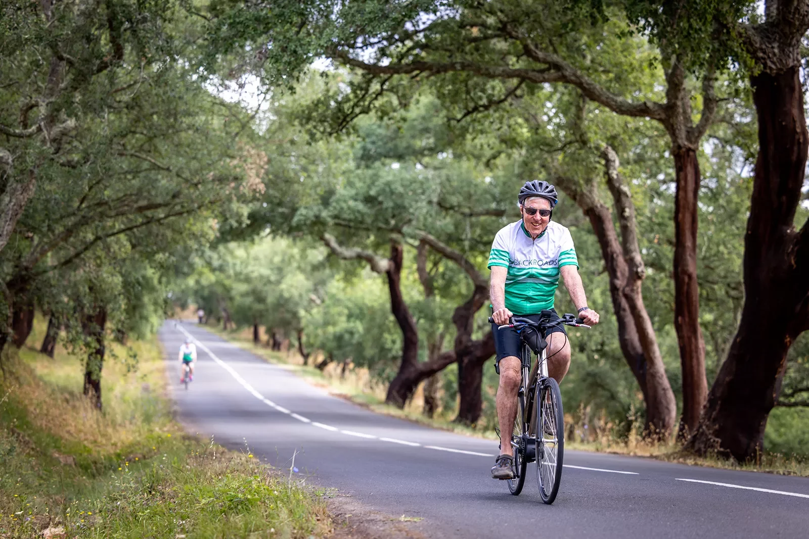 Biker riding along a tree lined road