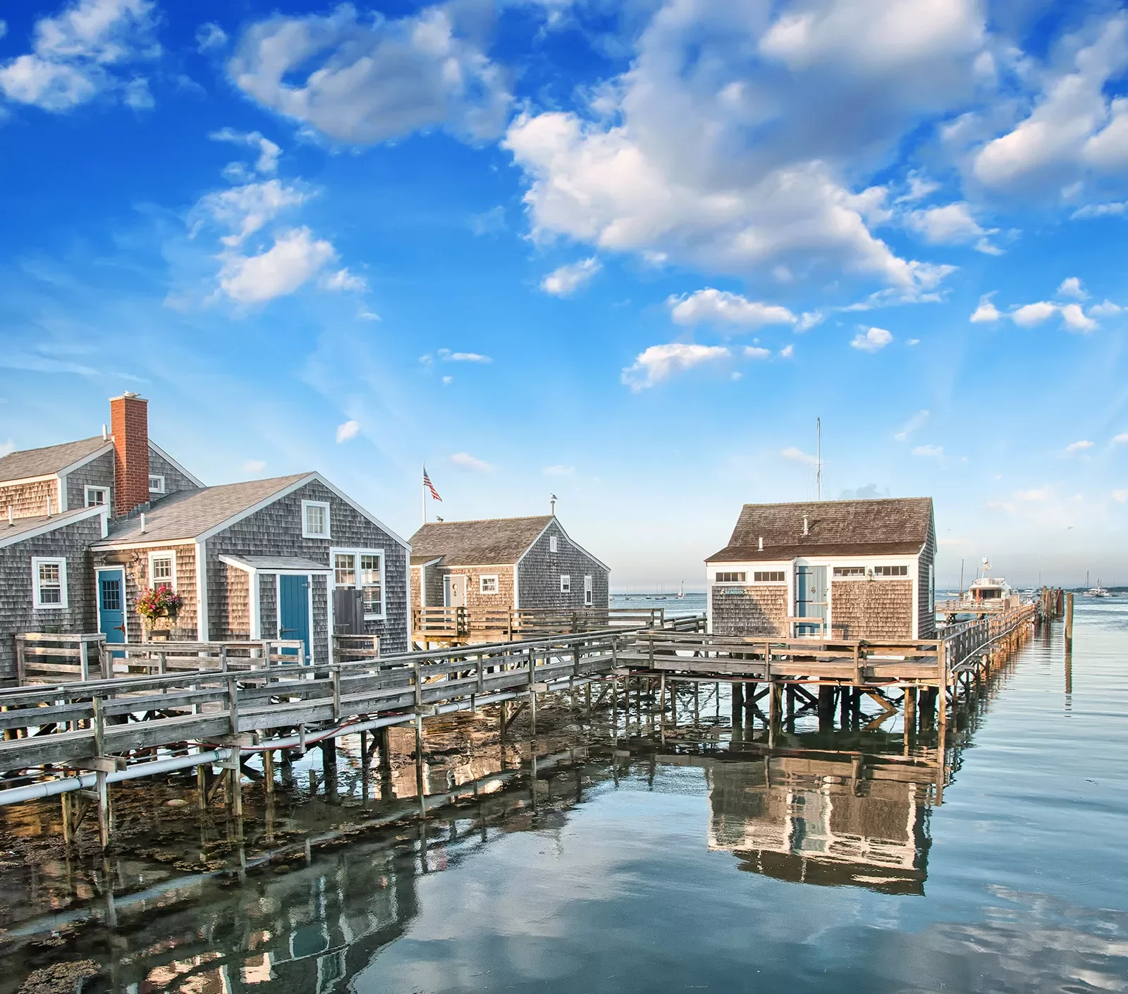 Shot of three small houses on the water, pier and small boat in background.