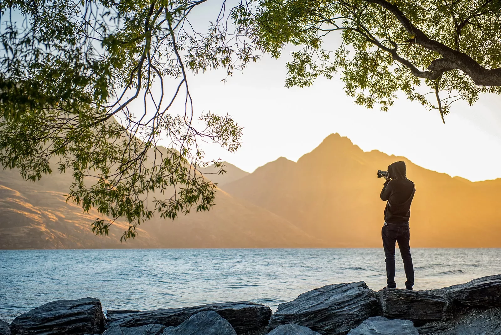 Single hiker taking a photo at the edge of a lake in New Zealand