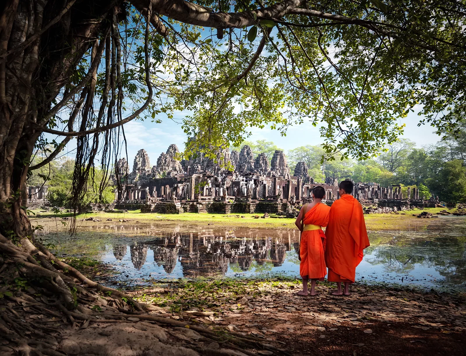 Two monks in traditional orange robes looking at Angkor Wat in Cambodia