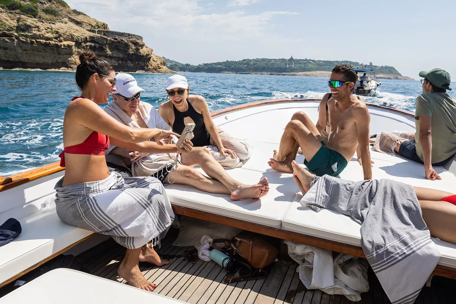 Six guests on boat, three looking at one of their phones.