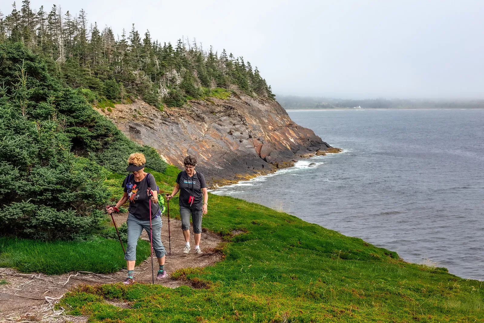 Two guests walking alongside coastal cliff.