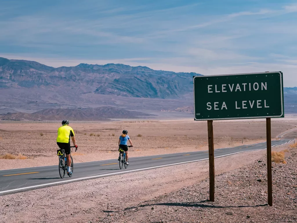 Cyclists on the road in California desert Elevation Sea Level sign