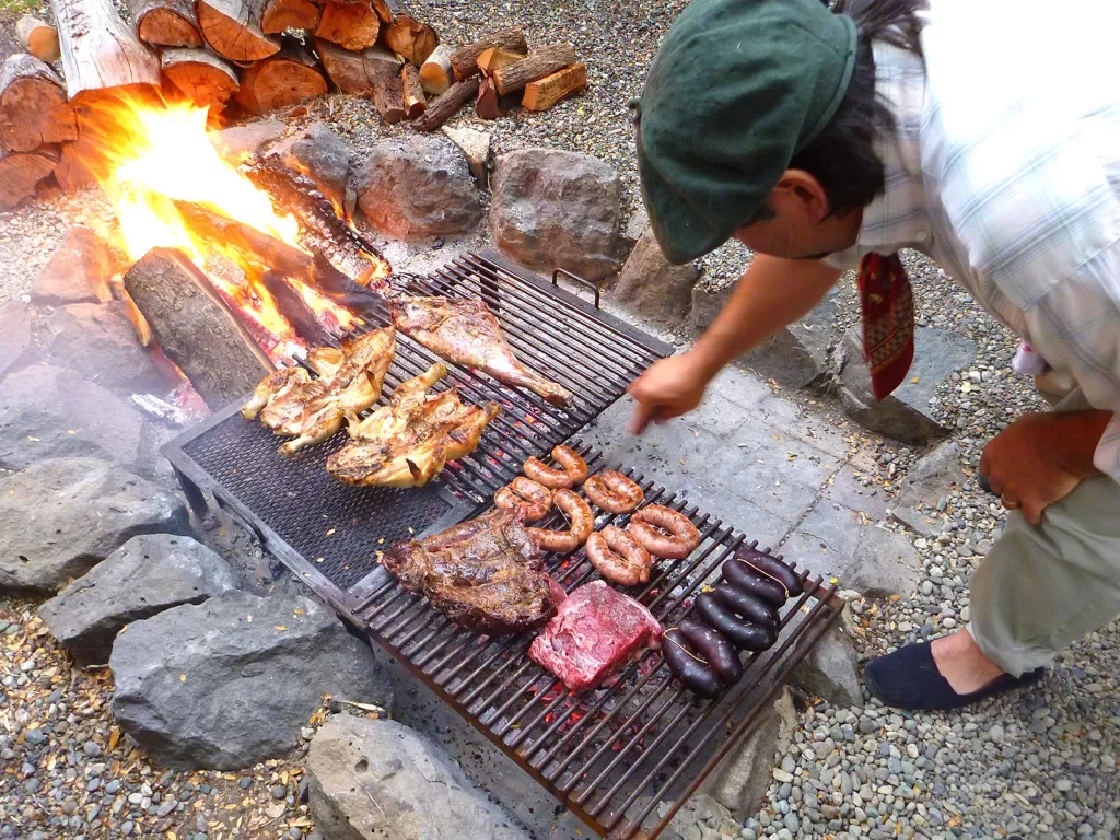 Shot of chef/local grilling meats over fire.
