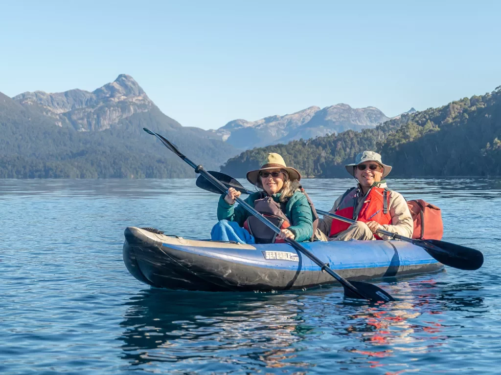 Two guests kayaking, sharp mountains in distance.