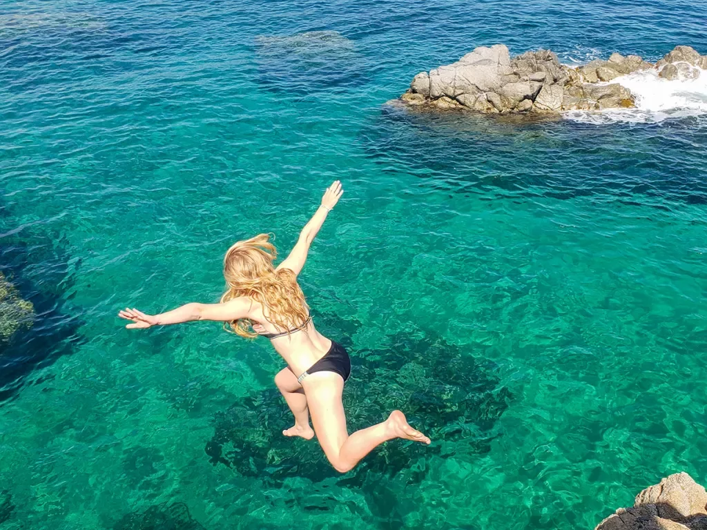 Teenage girl jumping into clear blue-green waters