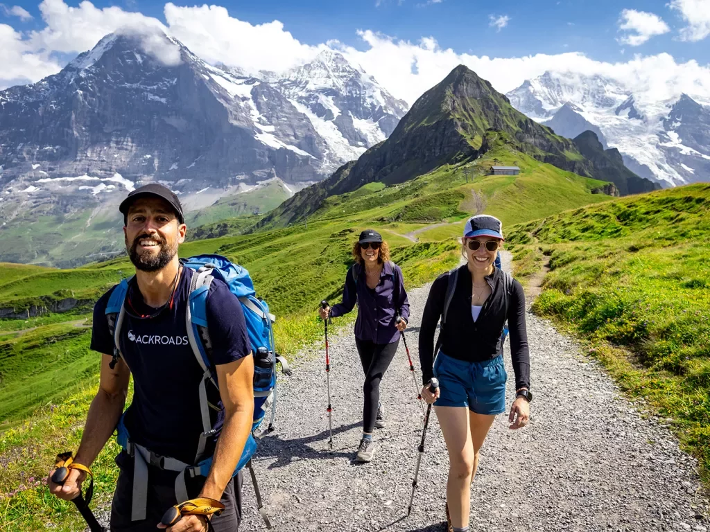 Three guests walking towards camera, Mount Eiger in background.