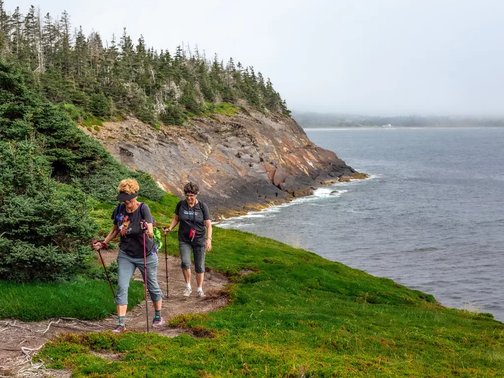 Two guests walking alongside coastal cliff.
