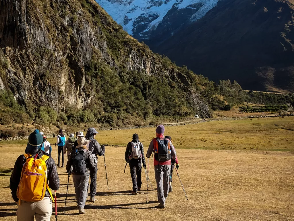 Group of hikers going through a dried field towards mountains