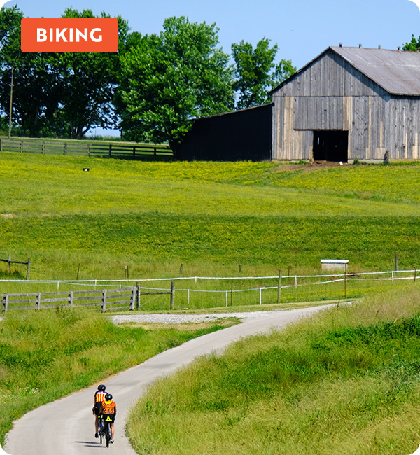 Two bikers riding through green grassy hills in Kentucky