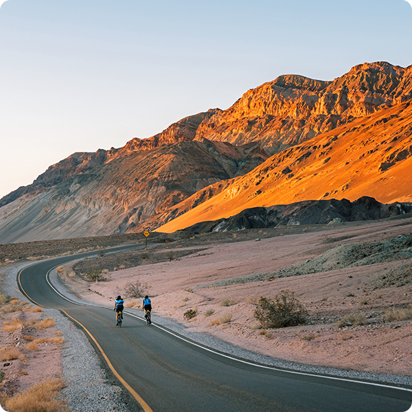 Two bikers riding along a winding road in Death Valley, California