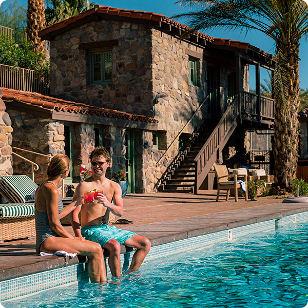 Two guests relaxing by a pool with beverages in Death Valley, California