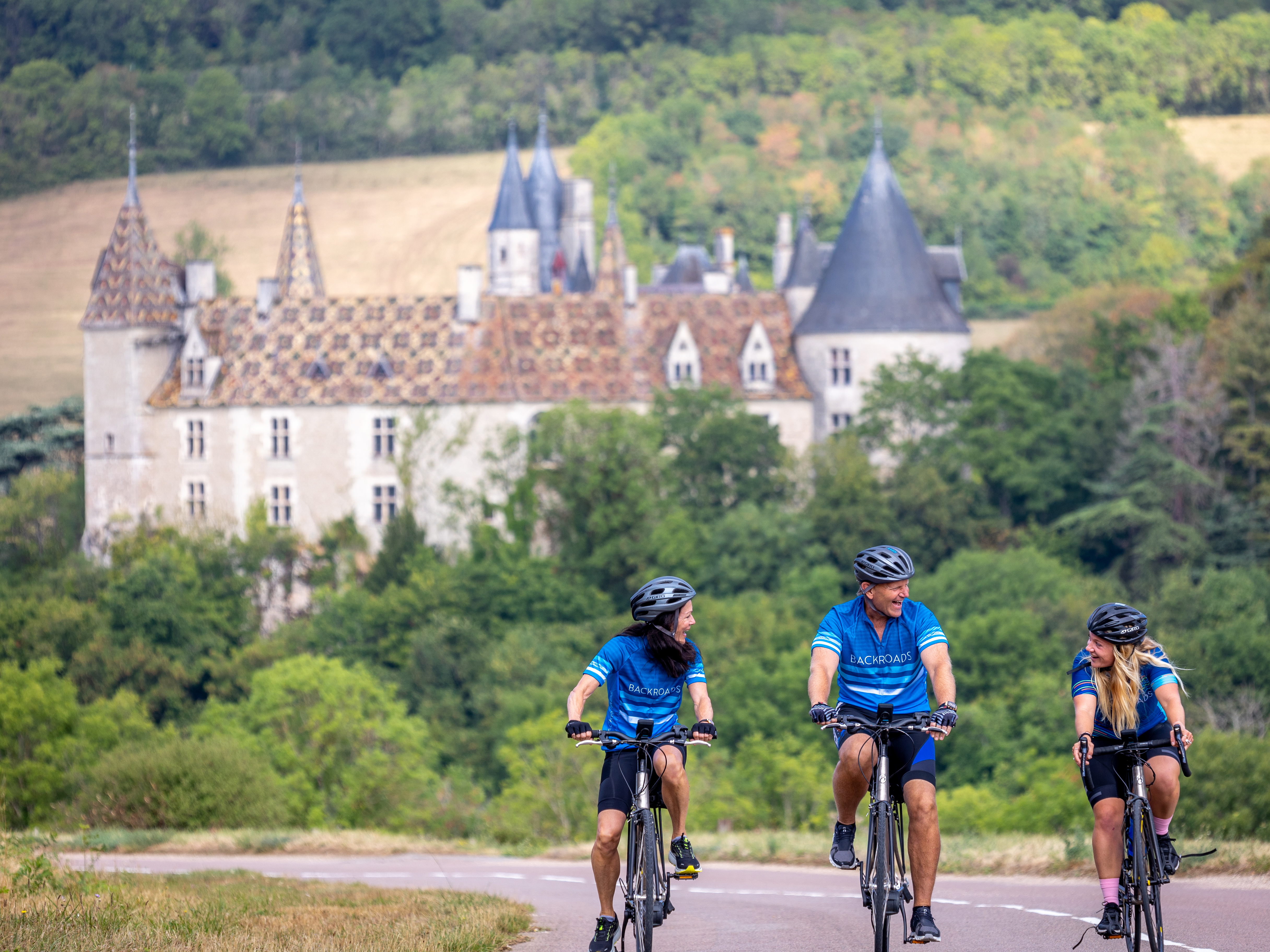 Three bikers riding away from castle in Burgandy, France.