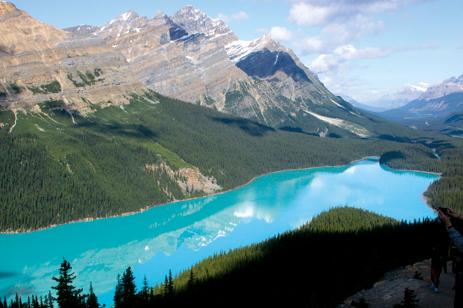 Wide shot of vibrant blue mountain river, snowy peaks in distance.
