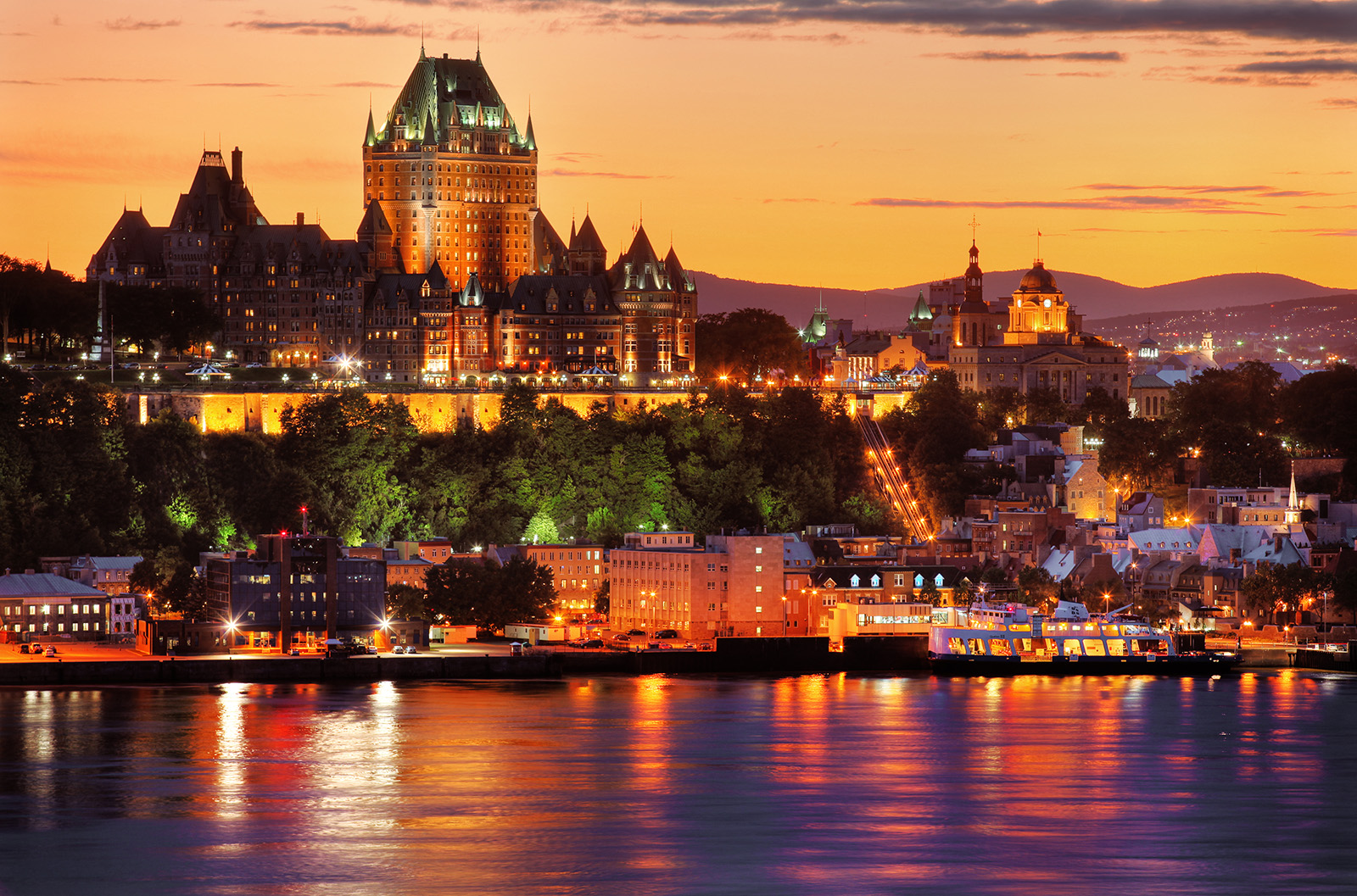 Wide shot of the Fairmont Le Château during sunset, river in foreground.