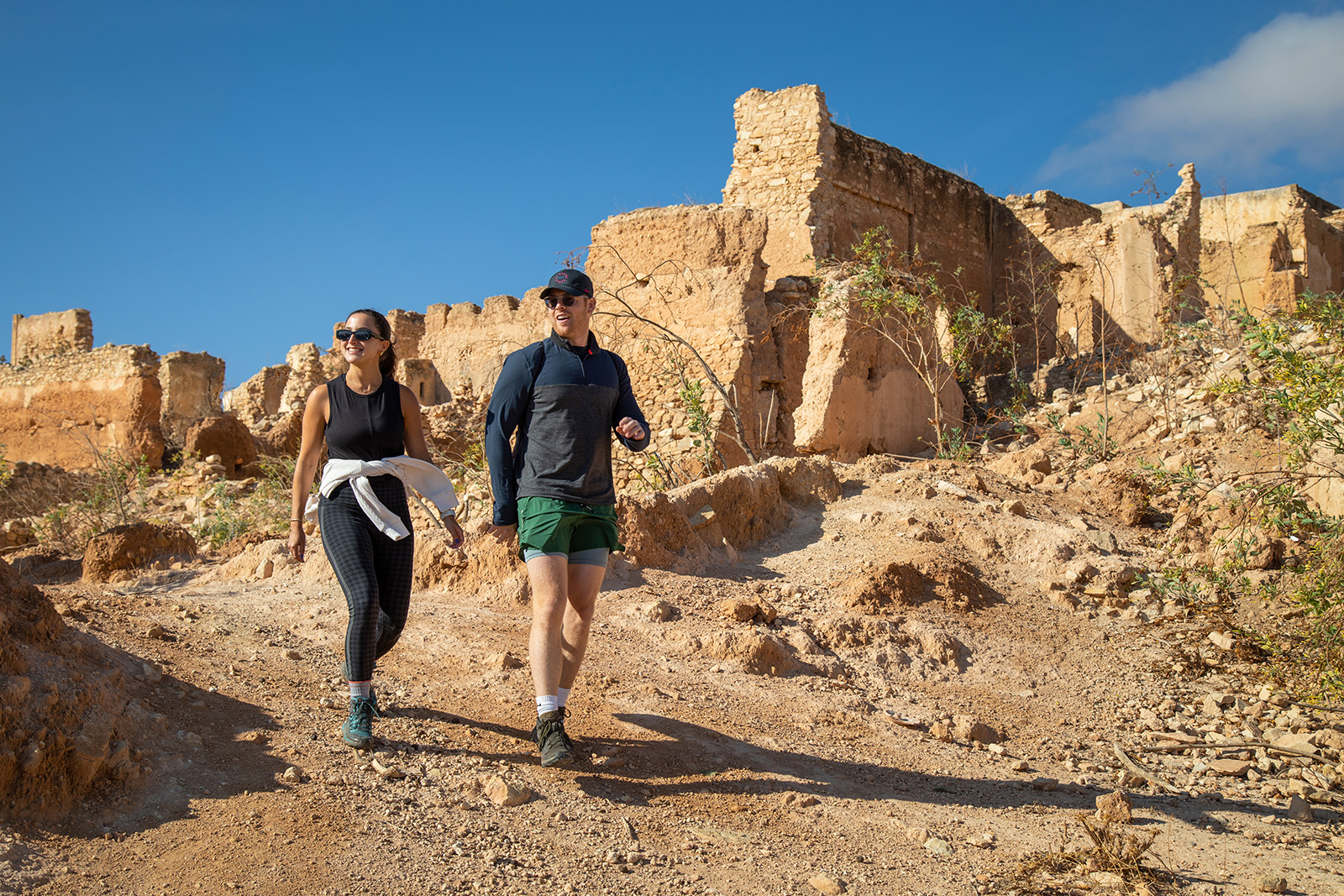 Hikers walking past an old village wall