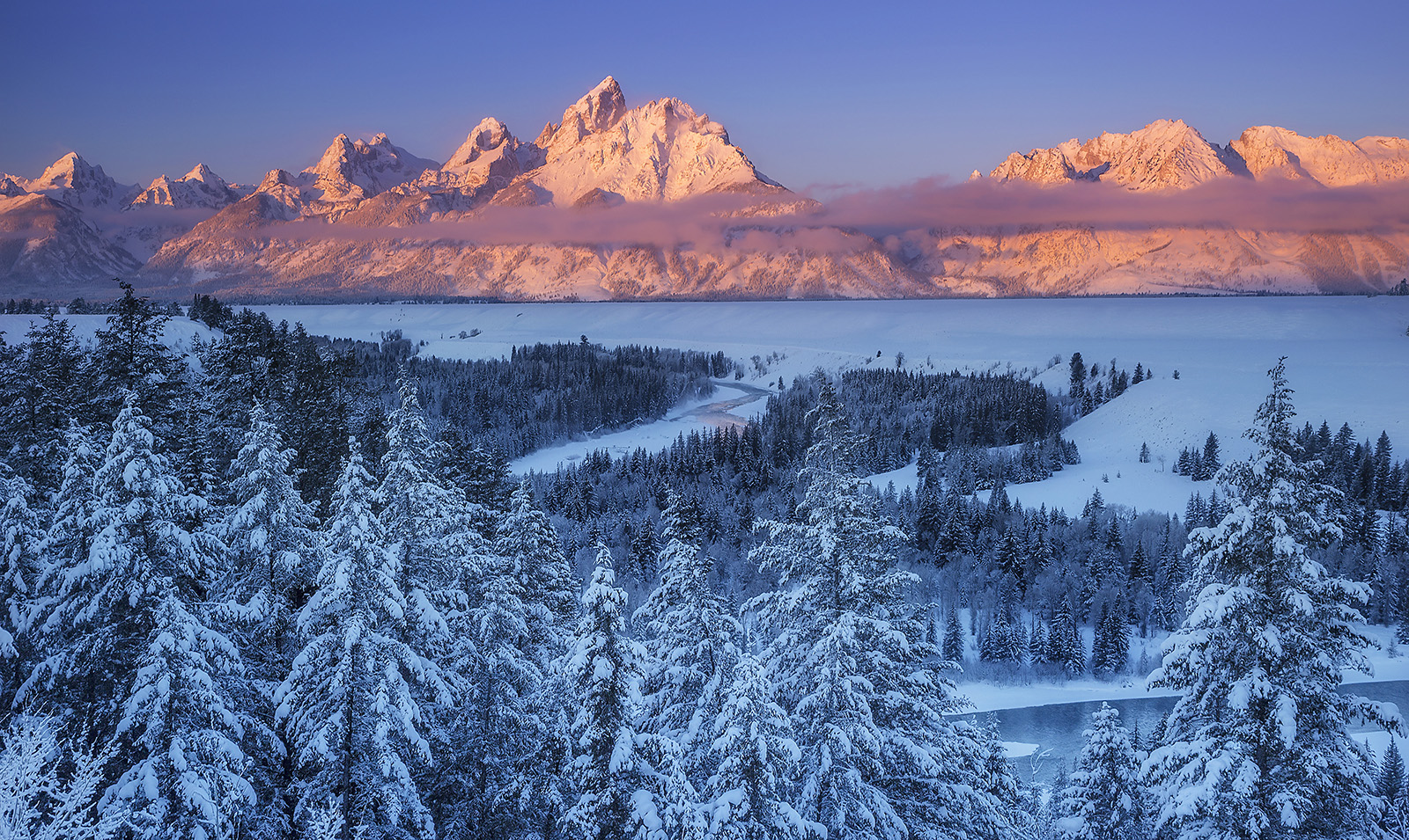 Snowy landscape with snow covered trees and orange sunset