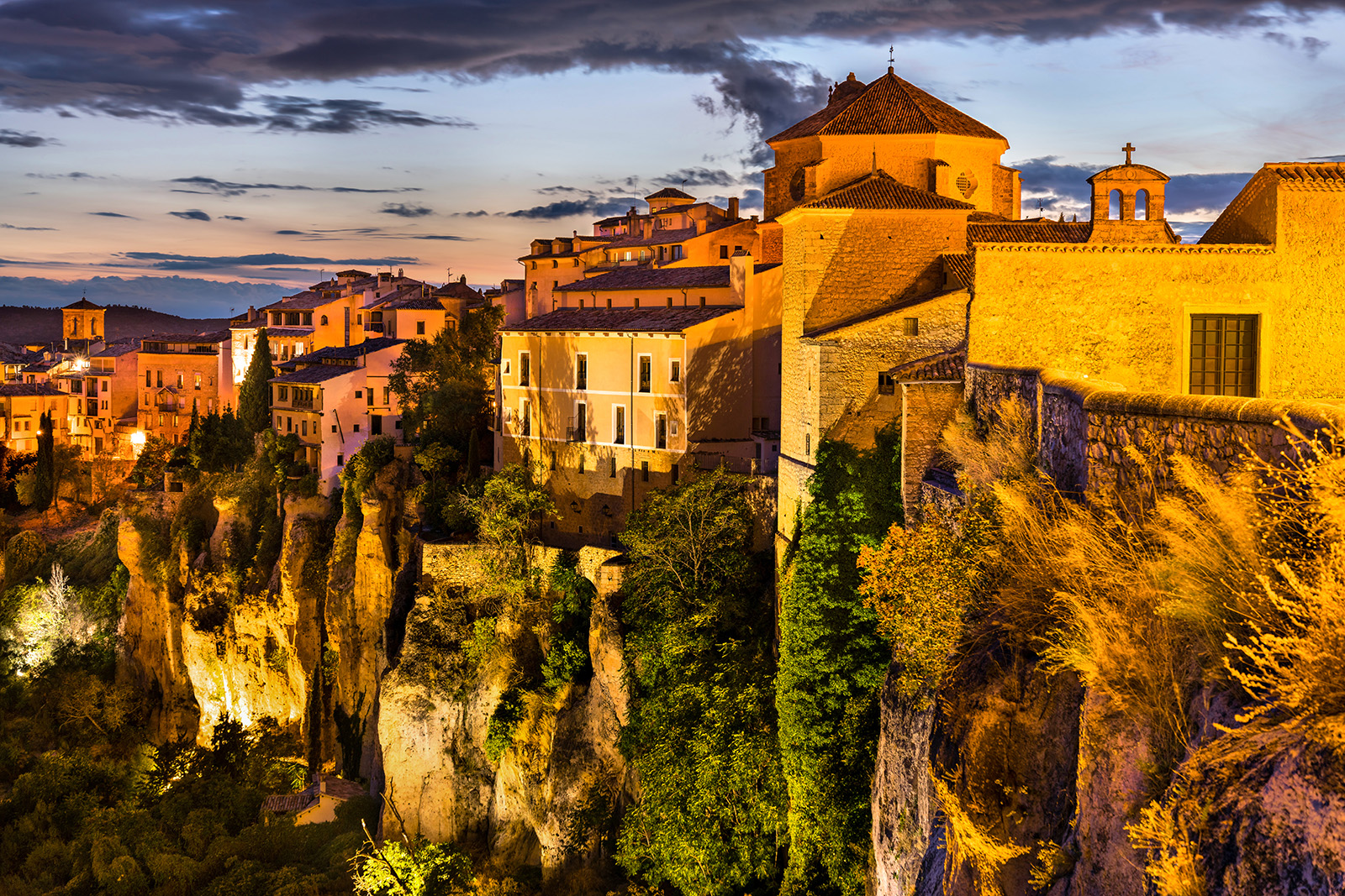 Sunset-lit cliffside, white houses above.