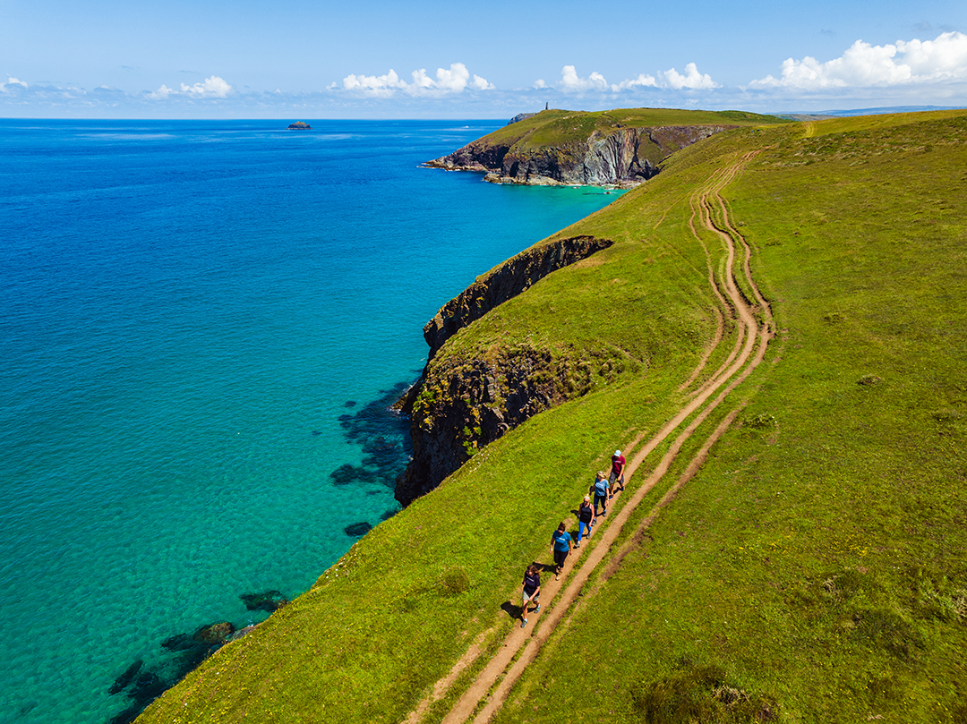 Dirt path along a grassy cliff, with the ocean on the left