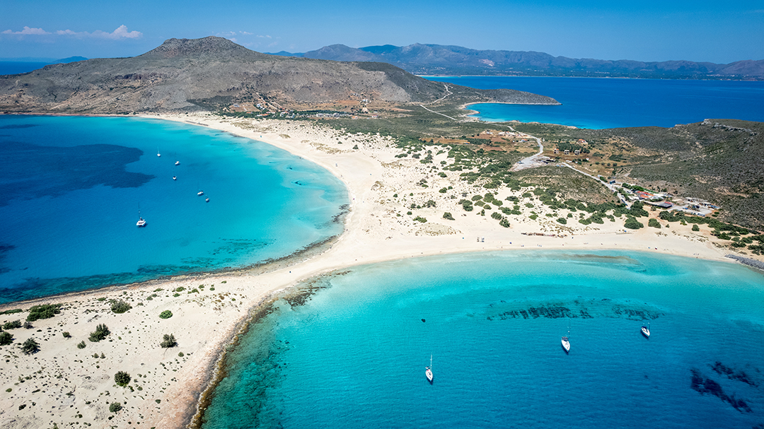 Two ocean coasts separated by a small pathway of way, with large mountains in the background