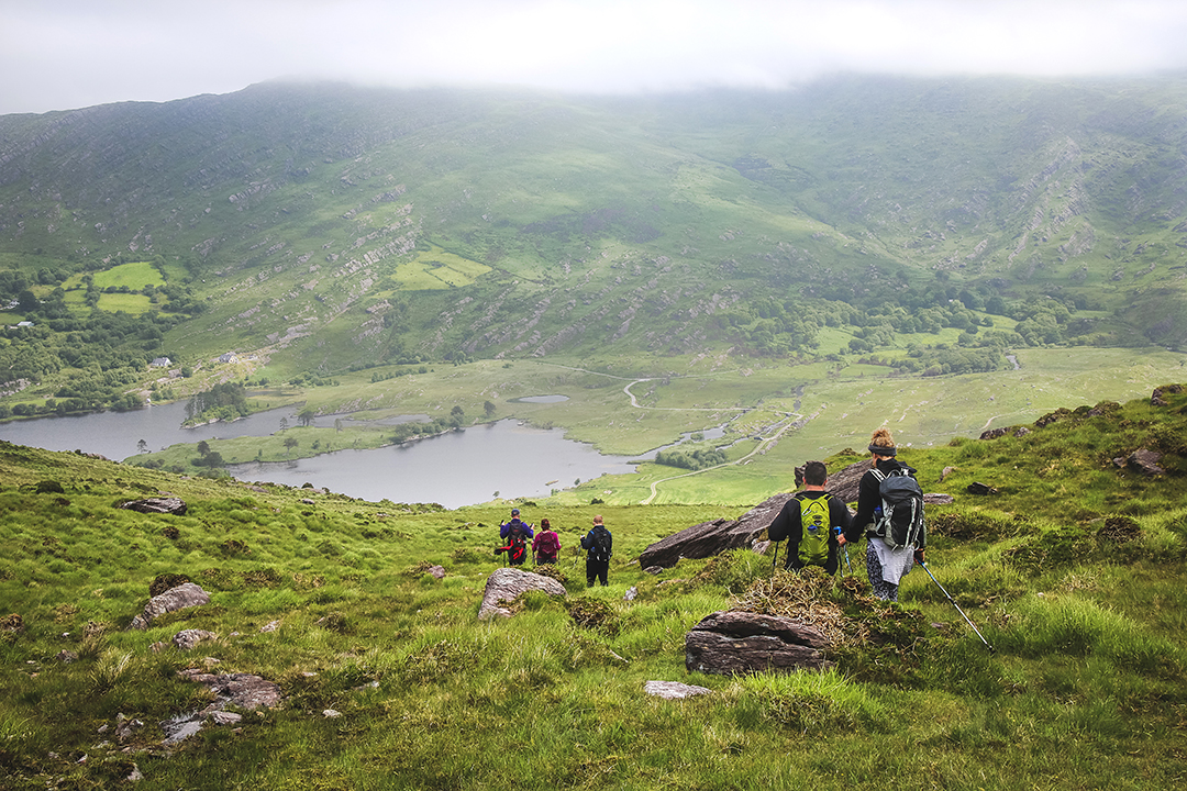 Group of people descended a hill, with foggy mountains in the distance