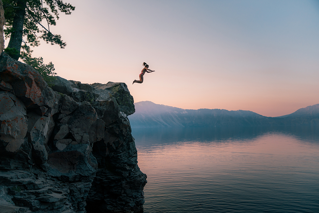 Woman jumping off a cliff into a lake