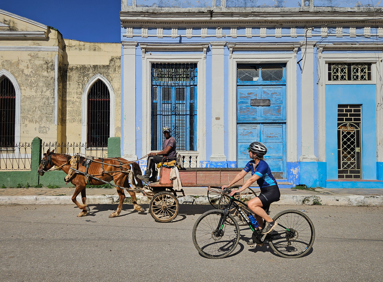 Woman riding a bike while looking at a man on a horse carriage