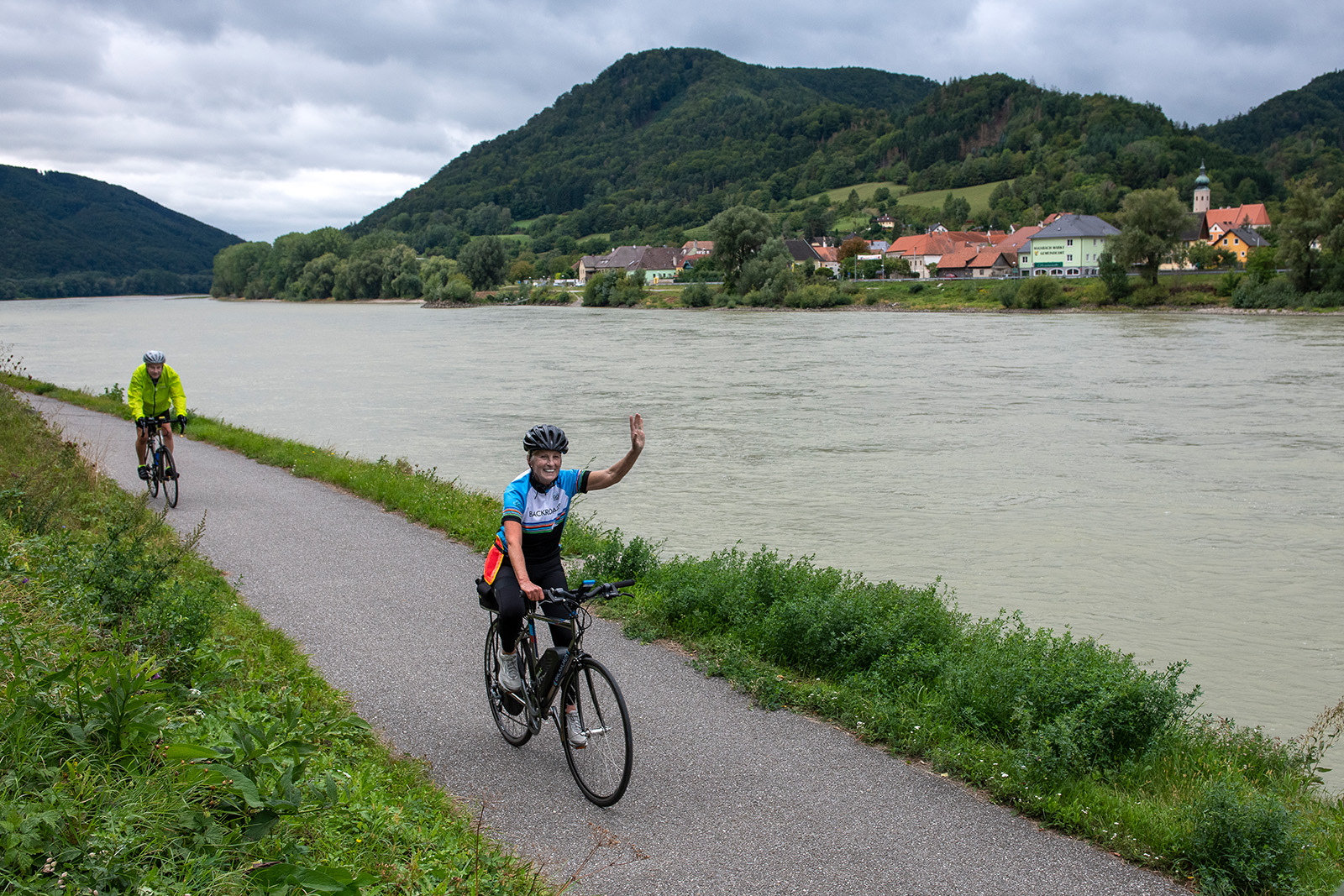 Woman riding a bike while raising her left hand