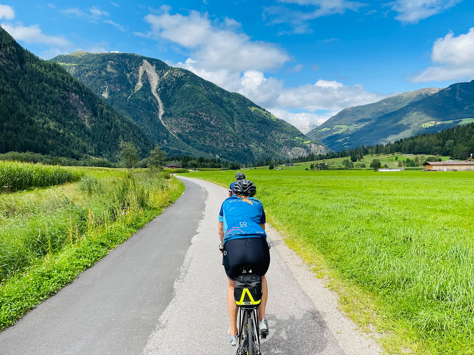 Back view of a biker on a road with mountains in the distance