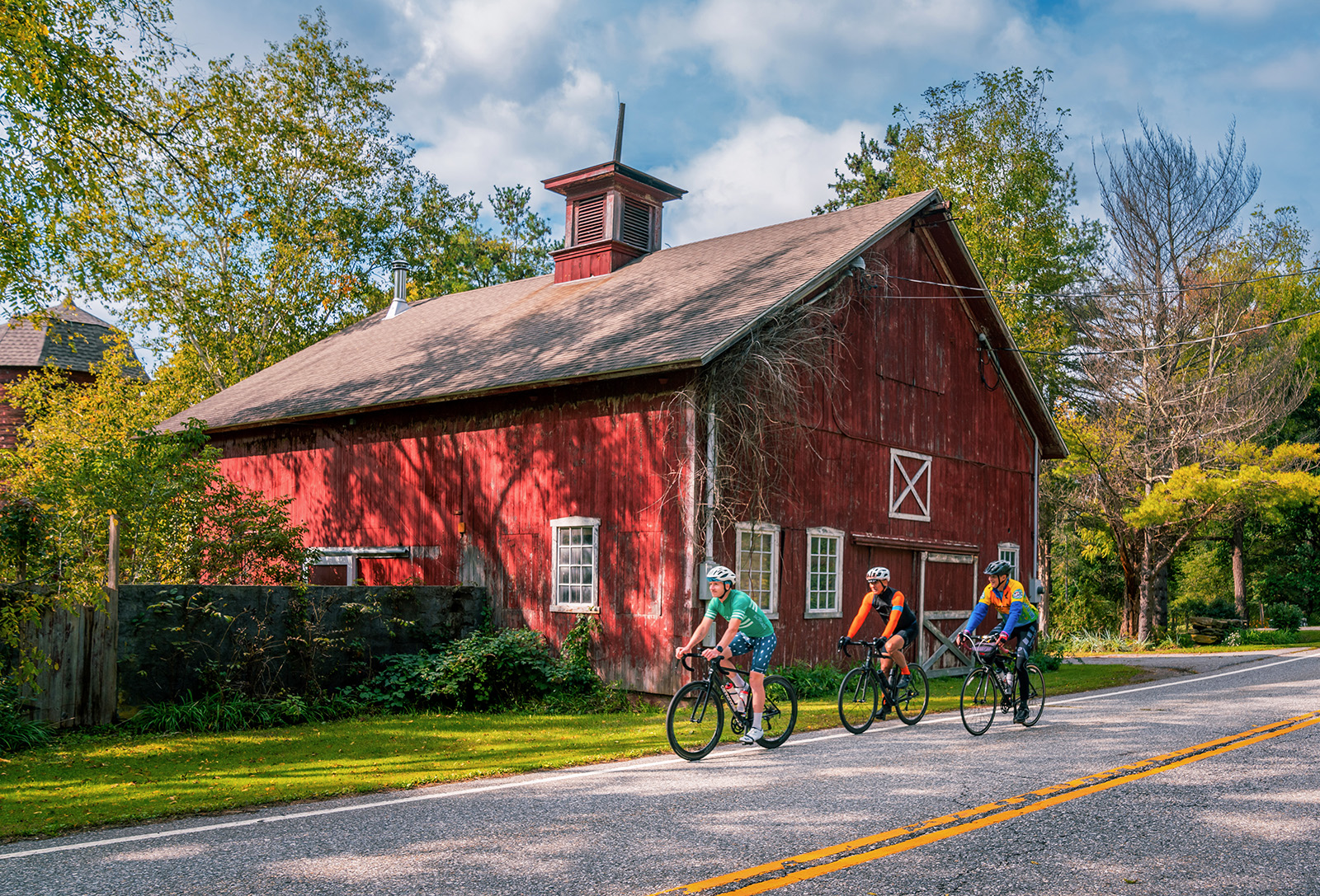 red house on the side of the road with bikers in front