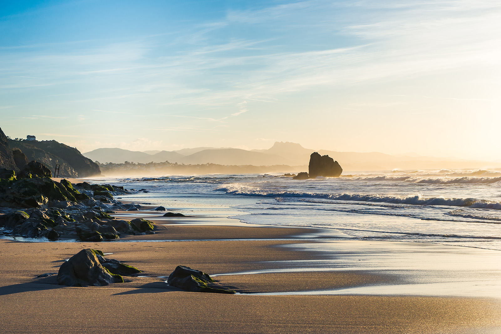 Ocean waves crashing into the sand and rocks during sunset