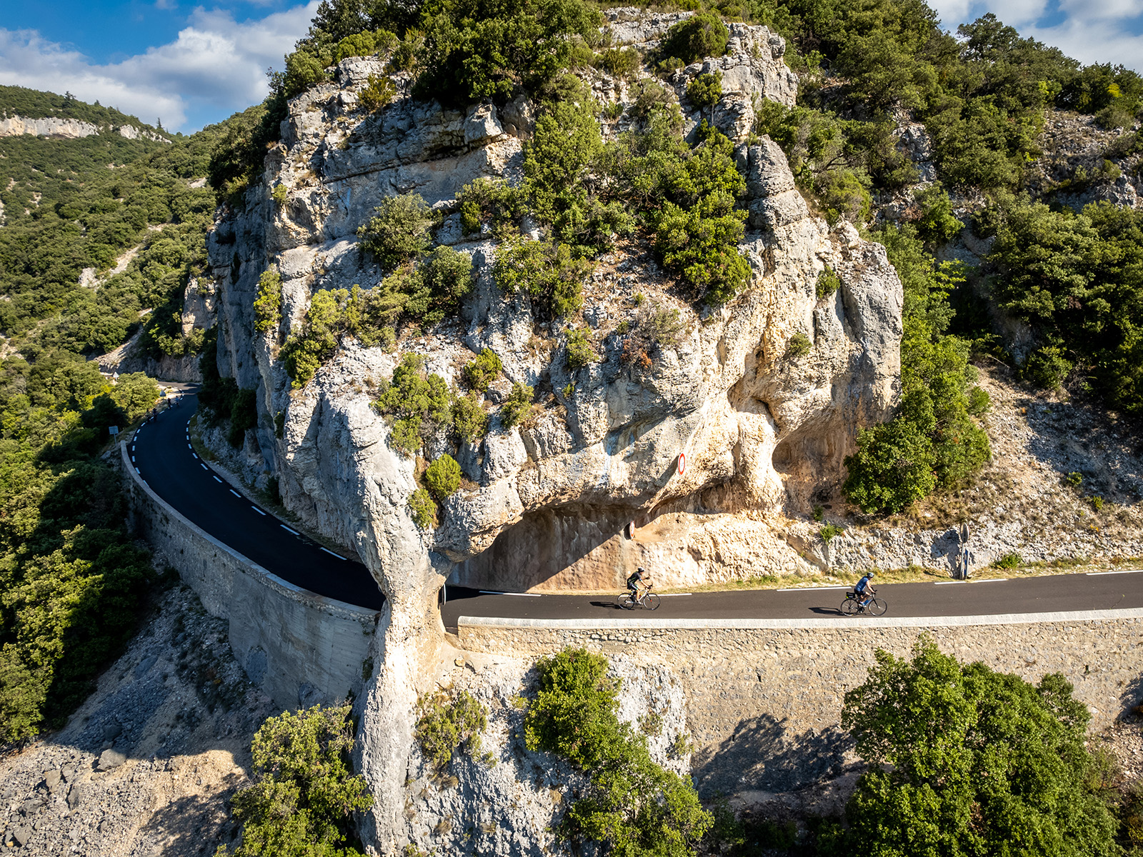 Road on a rocky cliff with two bikers on the road