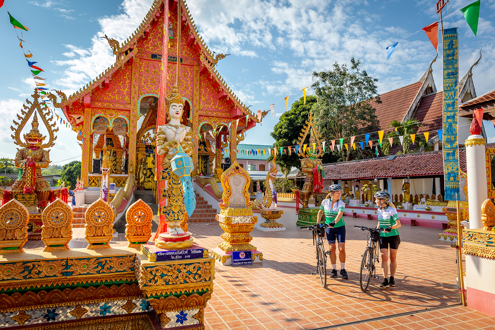 Two woman with bikes walking through a decorated town square