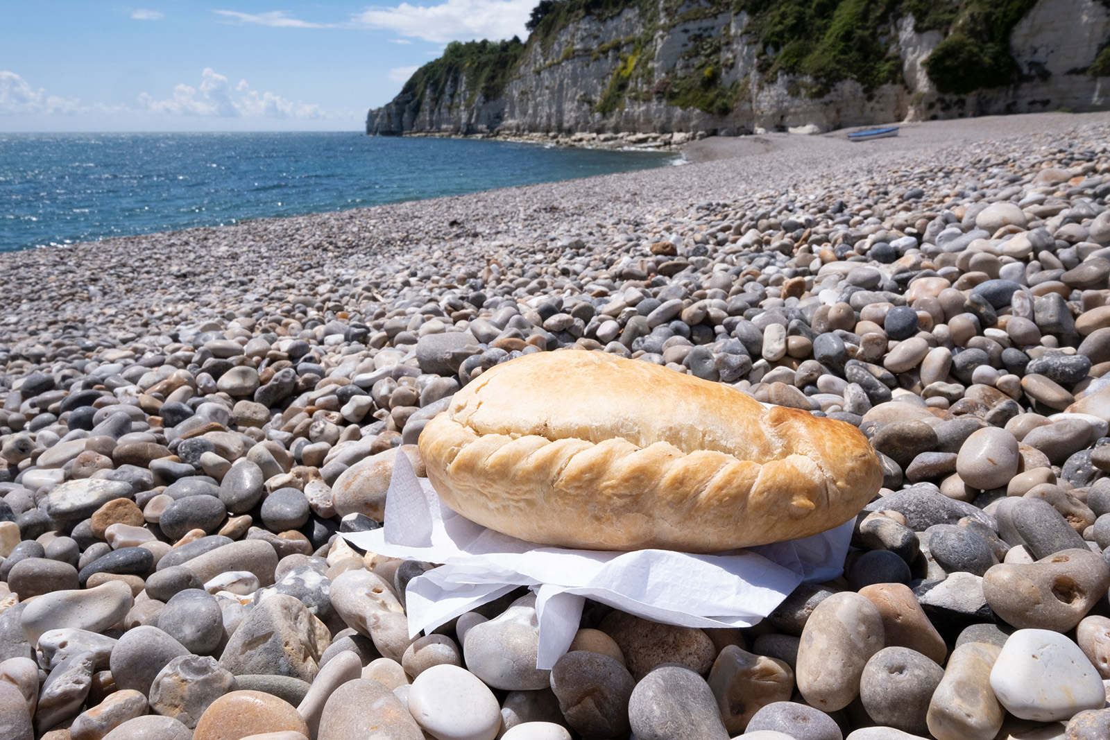 A puff pastry sitting on a napkin over rocks on the beach