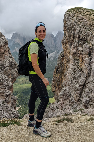 Woman wearing green and black, smiling on top of a rocky mountain