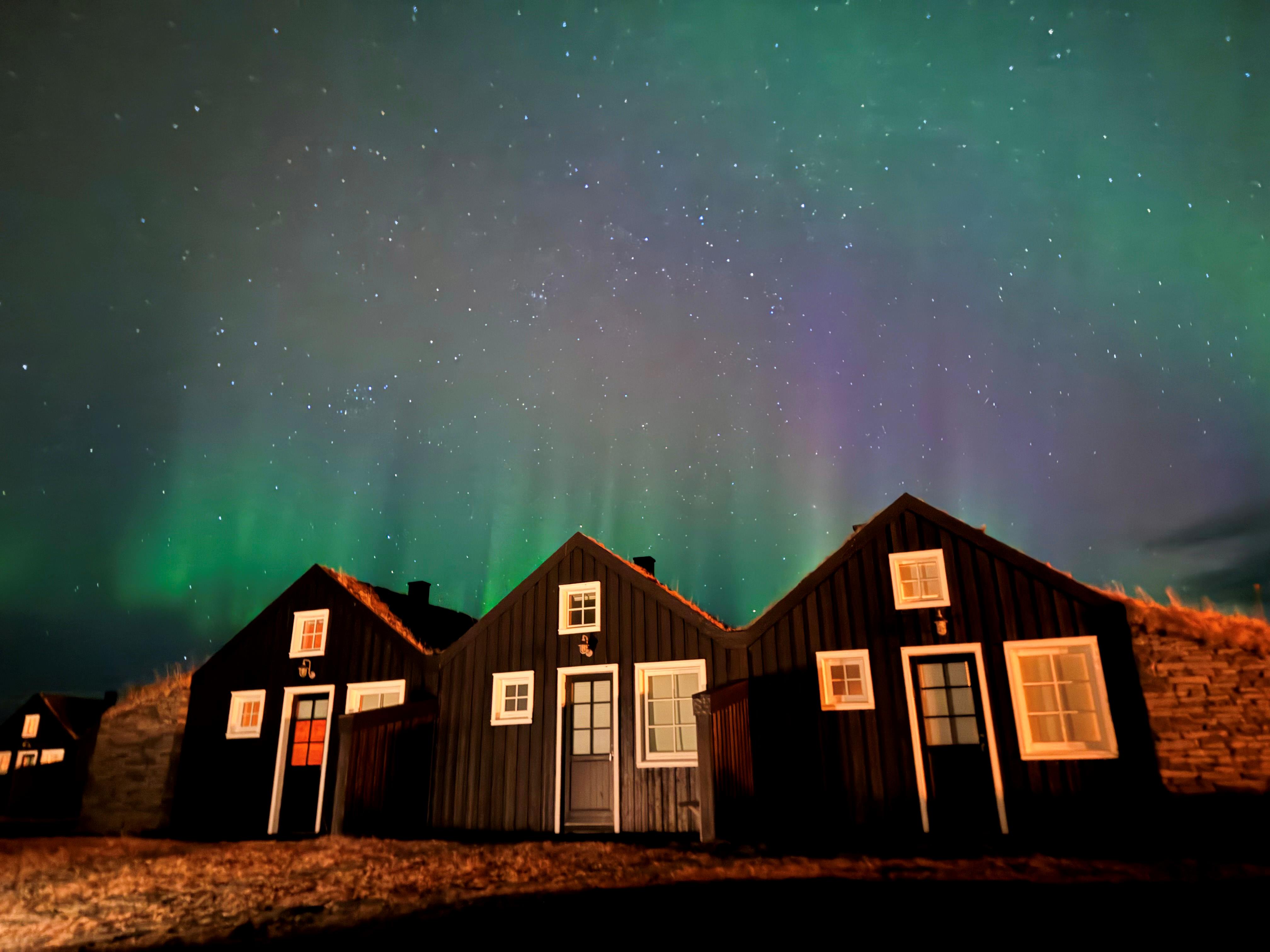 Three cabins with the Northern Lights in the sky