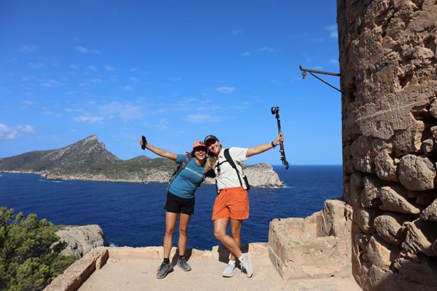 Man and woman with arms open in front of an ocean