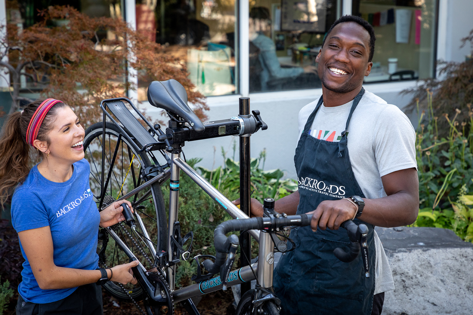 Man and women standing next to a bike, fixing the bike