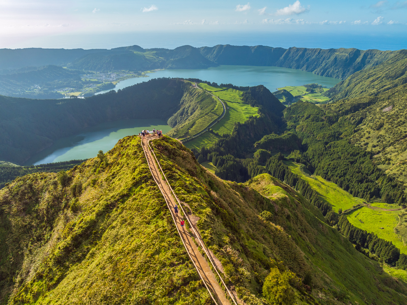 Sky view of a long path that sits on top of a long, grass-covered cliff