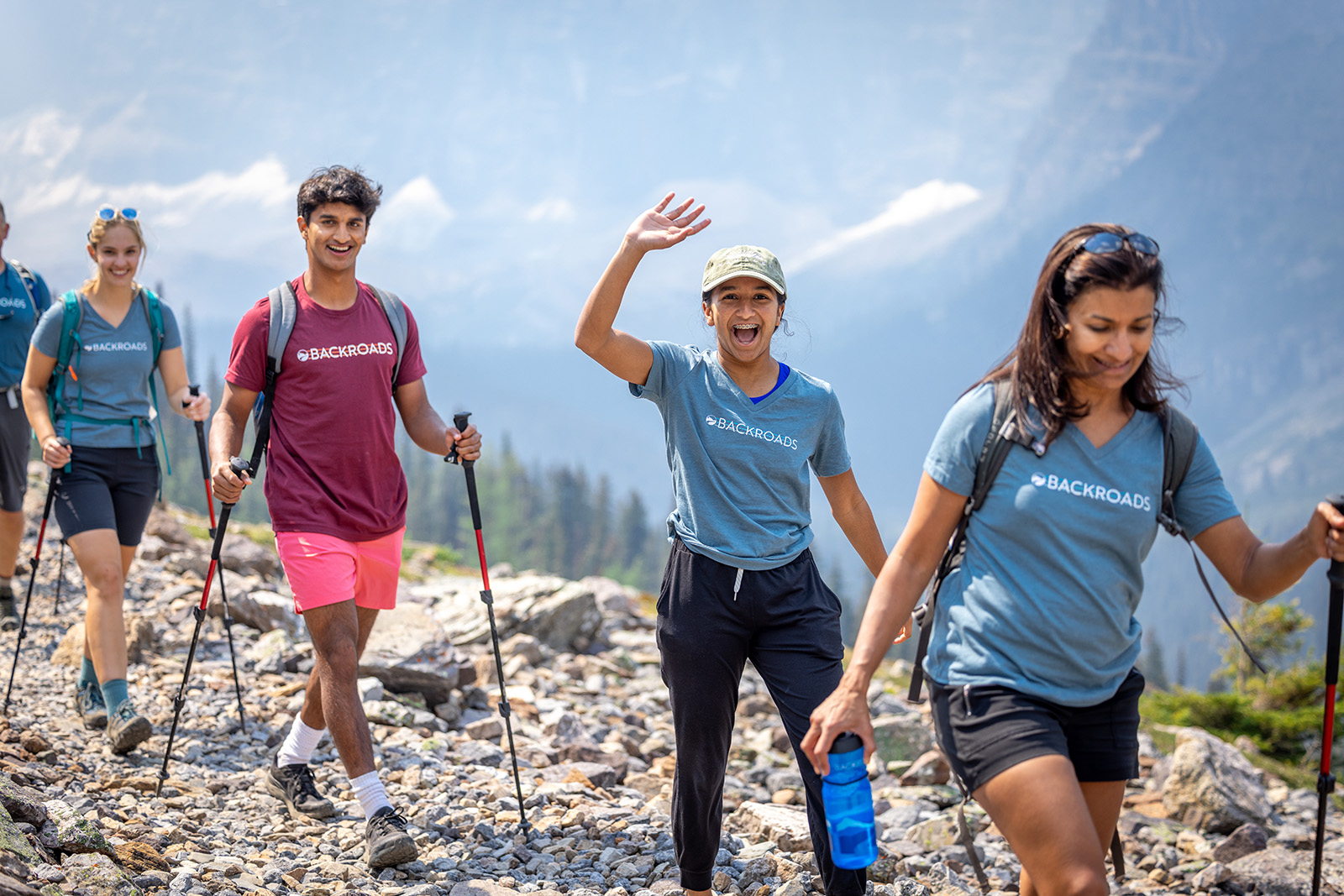 Group of hikers with walking sticks and waving at the camera